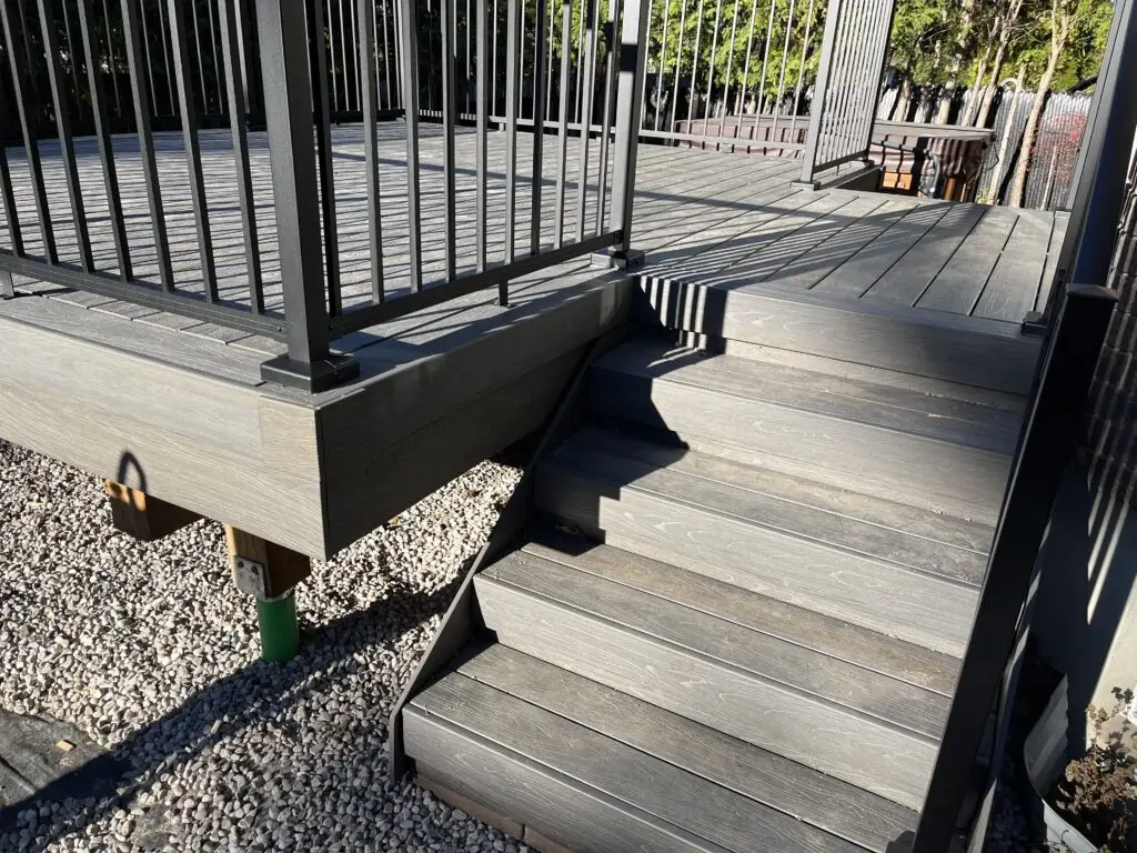 A finished set of composite deck steps with aluminum handrail